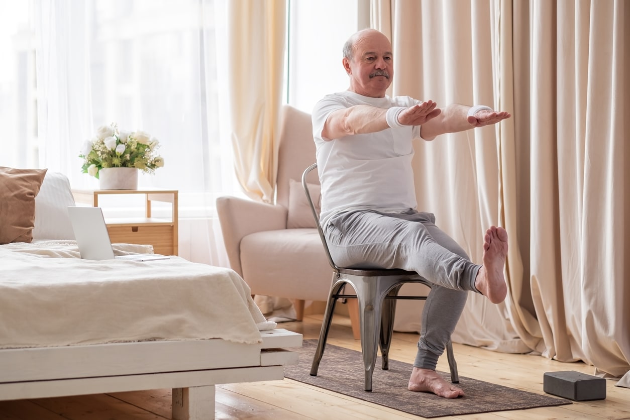 Man exercising using a chair in his bedroom