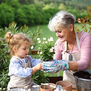 Grandmother wearing On the Go medical alert system gardening with granddaughter